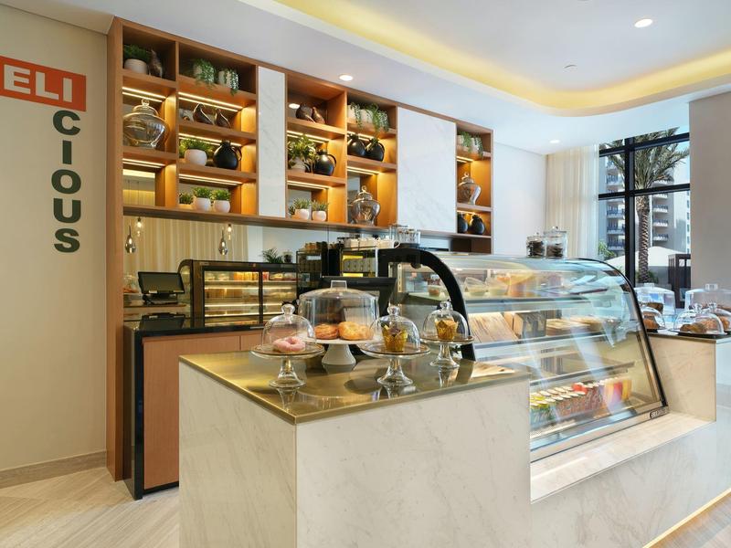 Innenansicht einer modernen Bäckerei mit Glasvitrinen, Regalen und hellen Wänden.