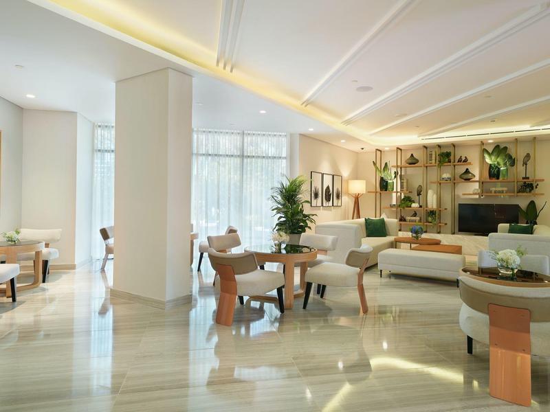 Heller moderner Warteraum mit Marmorboden, Pflanzen und stilvollen Sitzgruppen aus Holz und Stoff.