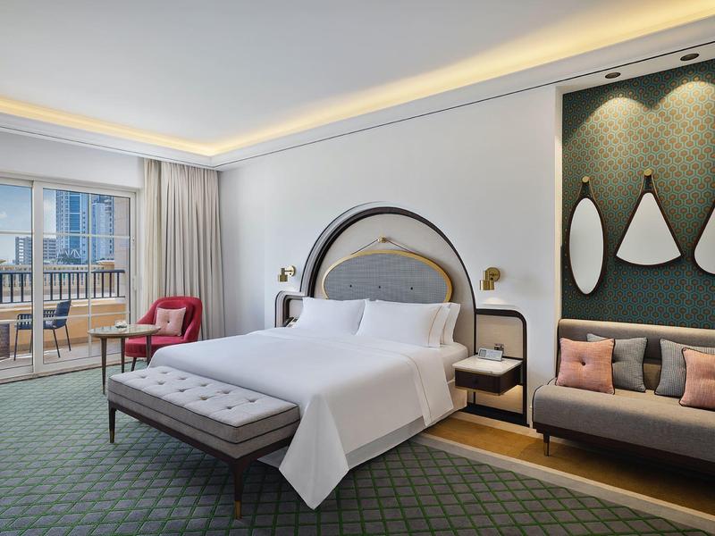 Modernes Schlafzimmer mit großem Bett, gepolstertem Sitzbank, Sofa, Teppich und Balkon mit Blick.