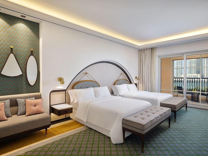 Modernes Hotelzimmer mit zwei Queensize-Betten, Sofa, Nachttischen und großem Balkon.