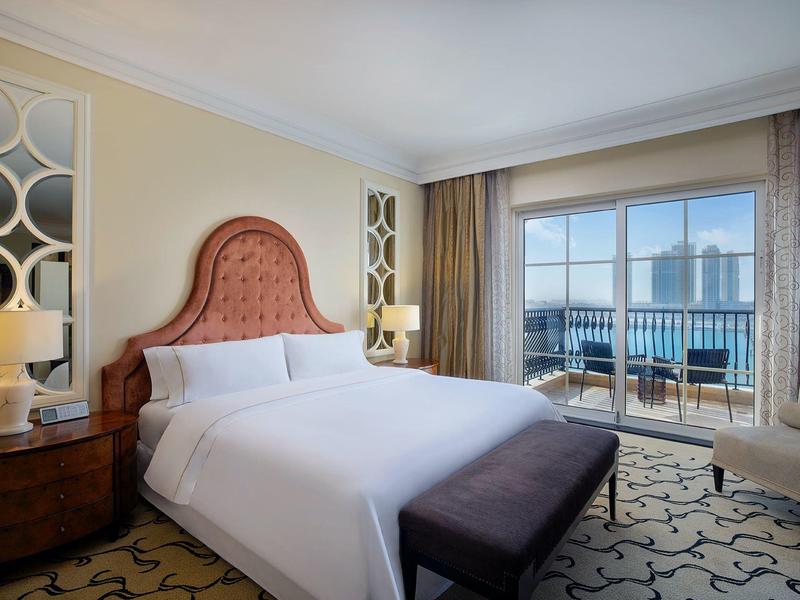 Helles Hotelzimmer mit großem Bett, braunem Kopfteil, Fenster mit Stadtblick und elegantem Teppich.