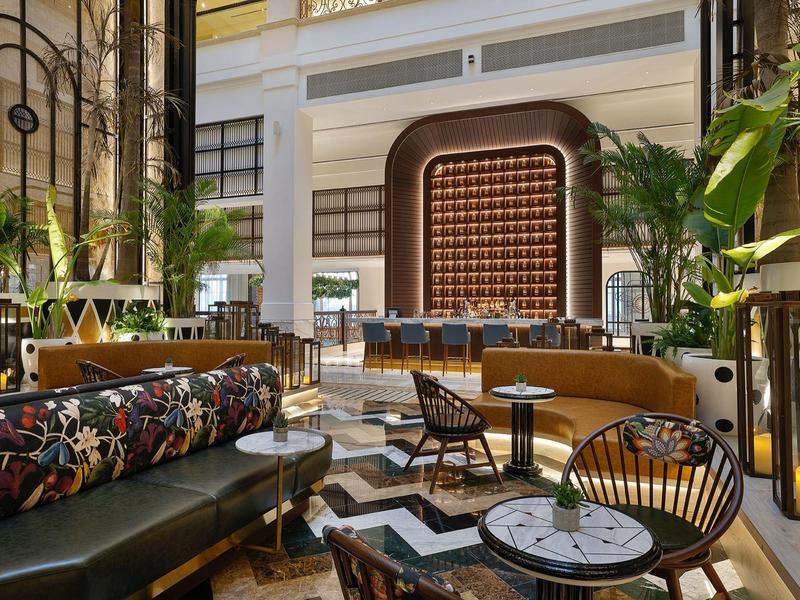 Elegante Hotel-Lobby mit modernen Sitzgruppen, Pflanzen und warmem Licht in hellem Ambiente.