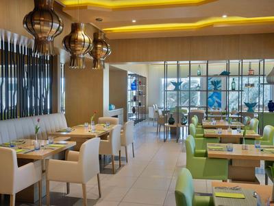 Modernes Restaurant mit elegantem Design, weißen und grünen Stühlen und großen Fenstern.