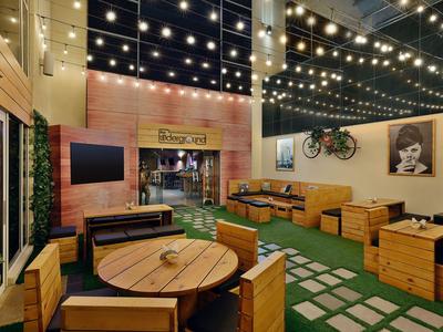 Ein eleganter Außenbereich mit Holzmöbeln, grüner Kunstpflanze und dekorativer Beleuchtung.