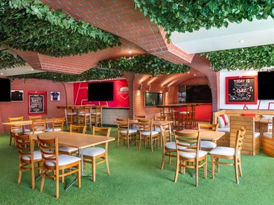 Gemütlicher Restaurantbereich mit Holztischen, Stühlen und begrünten Decken.