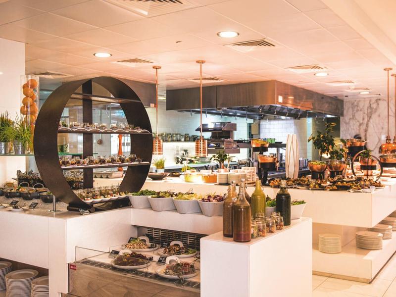 Moderner Markt mit weißen Verkaufsständen, Obst, Gemüse und rundem Holzregal in warmem Licht.