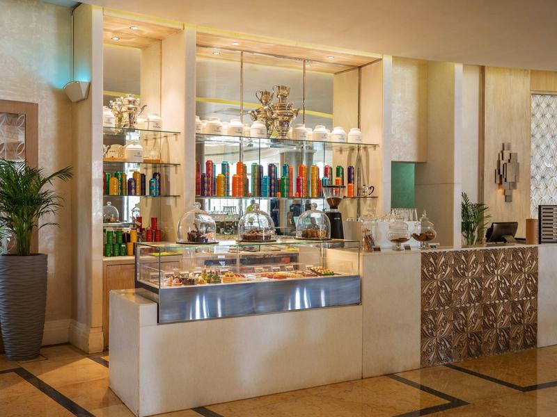 Moderner Kaffeebar mit bunten Flaschen, Glasvitrinen und dekorativen Elementen in warmem Licht.