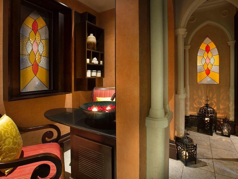 Gemütlicher Raum mit bunt gemustertem Fenster, rotem Sessel und dunklem Holzschreibtisch.