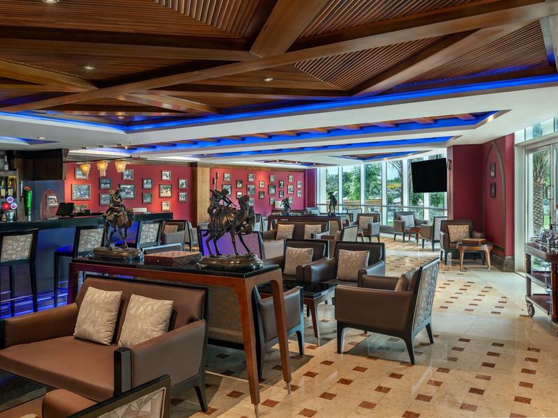 Moderner Hotelbarbereich mit Sitzgruppen, beleuchtetem Tresen und großem Fensterblick.