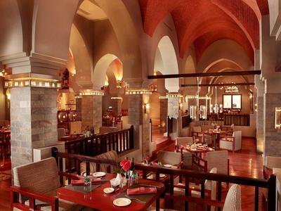 Großes Restaurant mit bogenförmigen Decken, roten Wänden, Holztischen und gedeckten Plätzen.