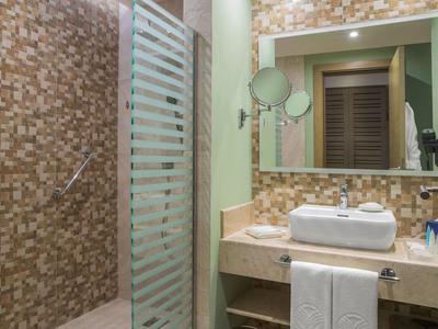 Modernes Badezimmer mit Mosaikwand, Glasdusche, großem Spiegel und Waschtisch mit rechteckigem Becken.