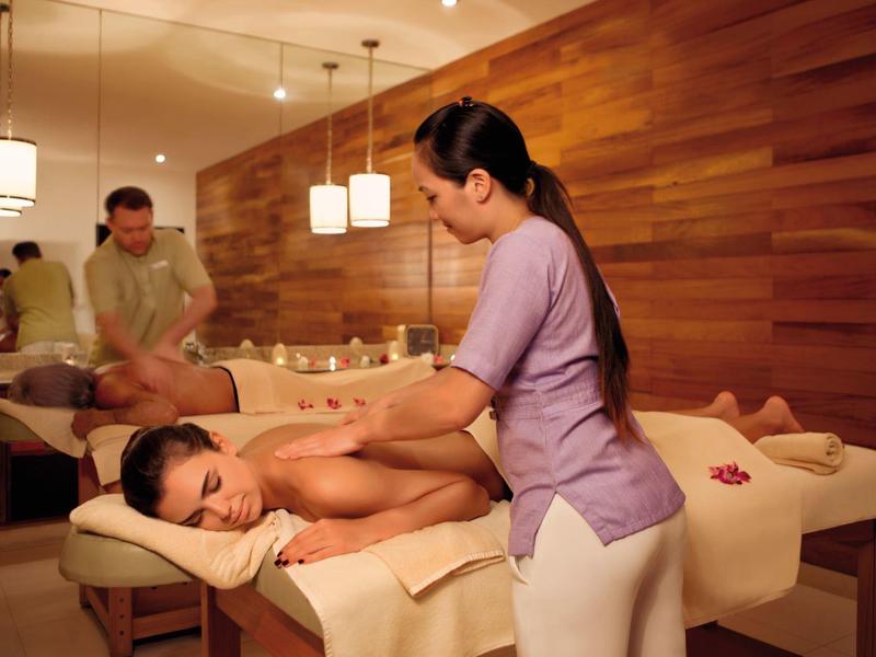 Frau bekommt Massage in warm beleuchtetem Spa mit Holzdekor und entspannter Atmosphäre.