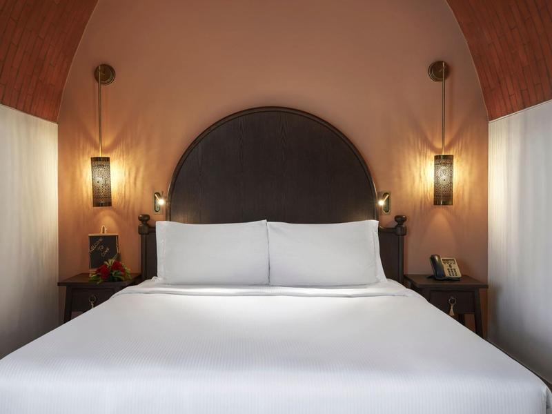 Doppelbett mit weißer Bettwäsche, schwarzem Kopfteil und zwei Nachttischen in warmem Holzdekor.