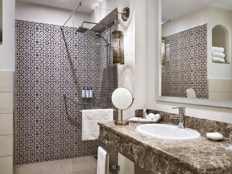 Innenaufnahme eines modernen Badezimmers mit Marmorwaschbecken und großer begehbarer Dusche.