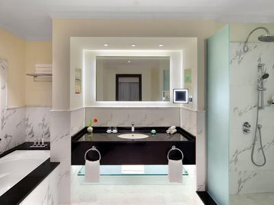 Modernes, helles Badezimmer mit großem beleuchtetem Spiegel und Duschkabine