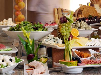 Buffet mit frischem Gemüse, Käse, Trauben und Aufschnitt auf weißen Tellern angerichtet.