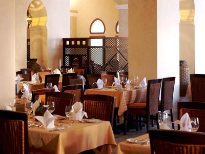 Elegantes Restaurant mit gedeckten Tischen, weißen Servietten und Holzstühlen in warmem Licht.