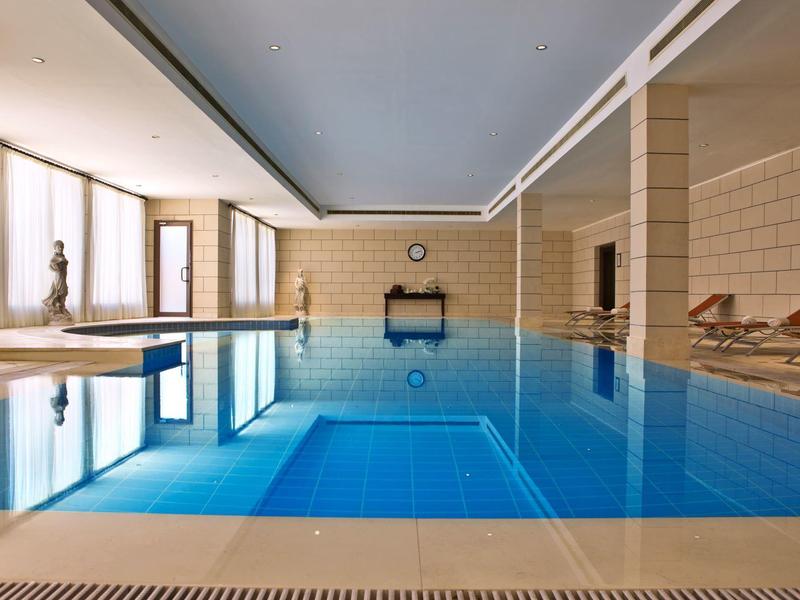 Moderner Innenpool mit klar blauen Wasser und bequemen Liegestühlen in einem Hotel.