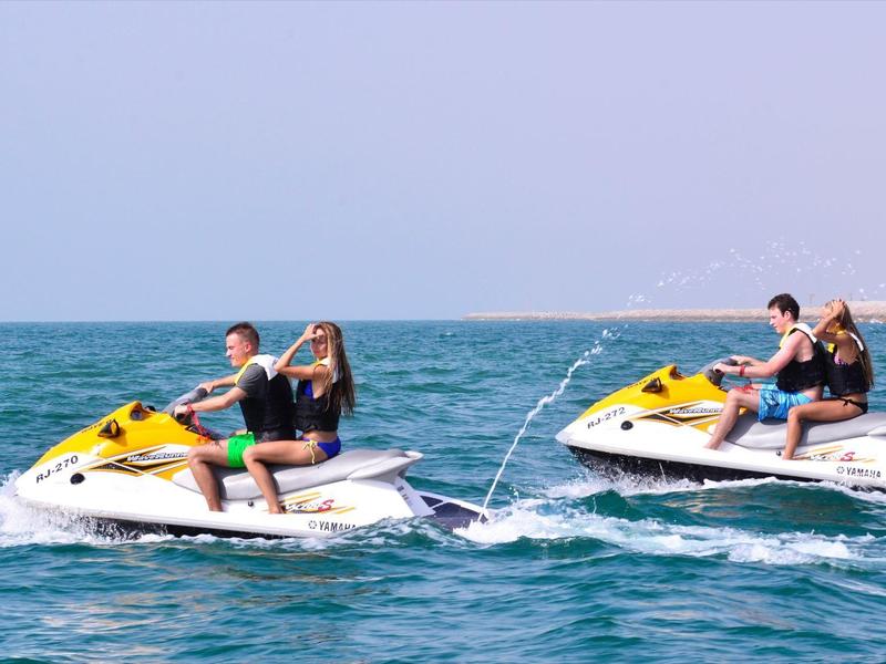Zwei Paare auf Jet-Skis fahren auf dem offenen Meer bei sonnigem Wetter.