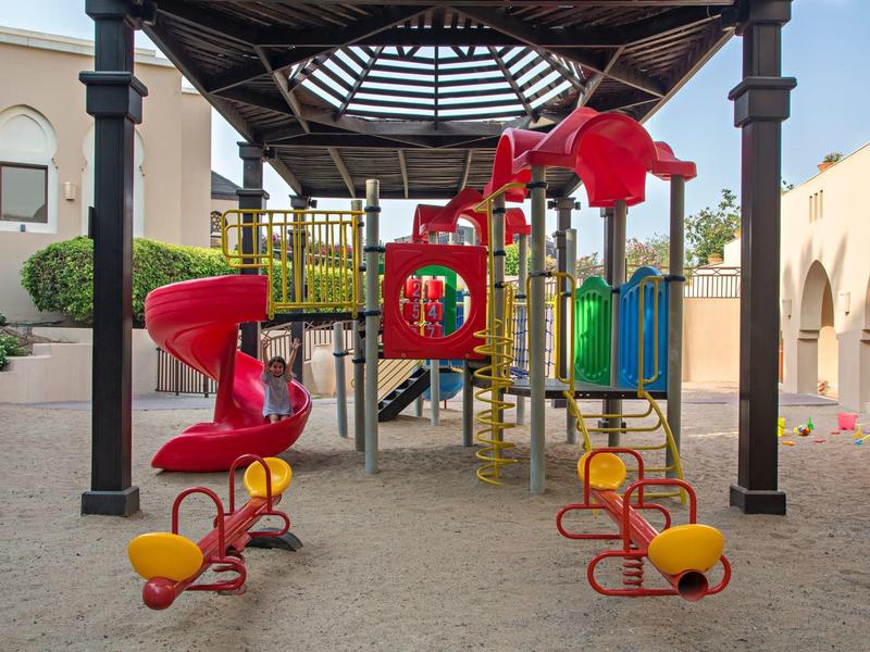 Bunter Spielplatz unter einem Pavillon in einer ruhigen Wohngegend mit Sandboden.