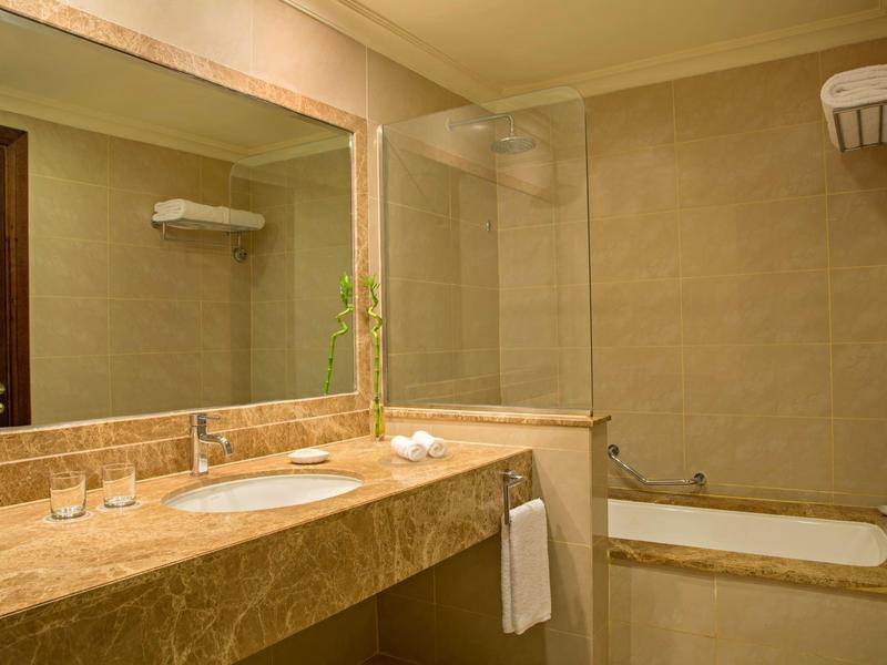 Modernes Badezimmer mit großem Spiegel, Waschtisch und Badewanne in neutralen Farbtönen.