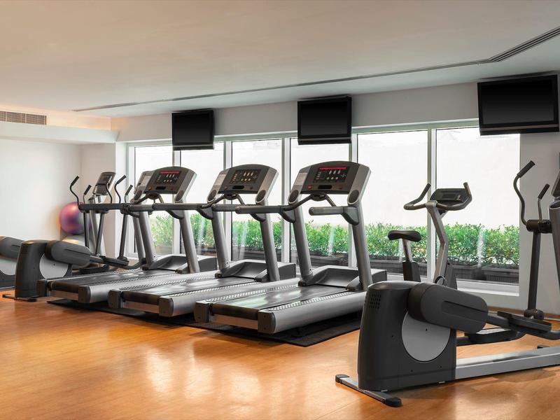 Modernes Fitnessstudio mit Laufbändern und Ergometern vor großen Fenstern