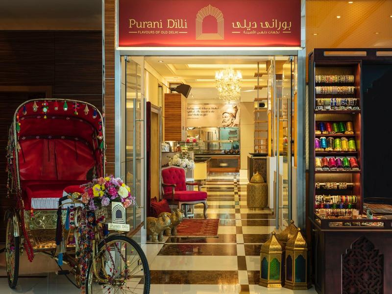 Eingang eines traditionellen Ladens mit dekorativer Rikscha und bunten Teeverpackungen.