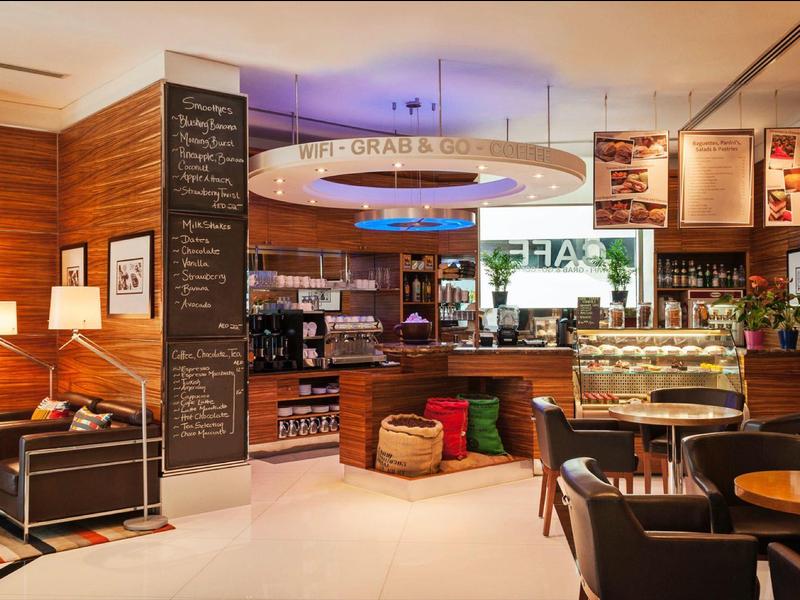 Moderner Café-Innenraum mit Holzvertäfelungen, Sitzgruppen und beleuchtetem Thekenbereich.