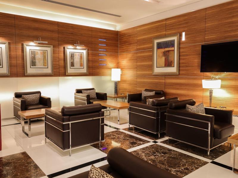 Modernes Wartezimmer mit schwarzen Ledersesseln, Holzvertäfelung und weißen Wänden.