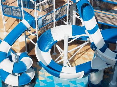 Große blaue und weiße Wasserrutschen in einem Schwimmbad mit Metalltreppen und Plattformen.