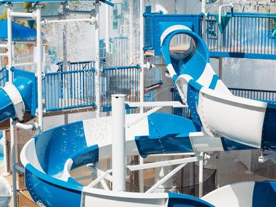 Mehrere blaue und weiße Wasserrutschen mit Metallgeländern und Stützen in einem Schwimmbad.