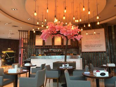 Modernes Café mit runden Tischen, grauen Stühlen und einem großen Blumenarrangement an der Decke.