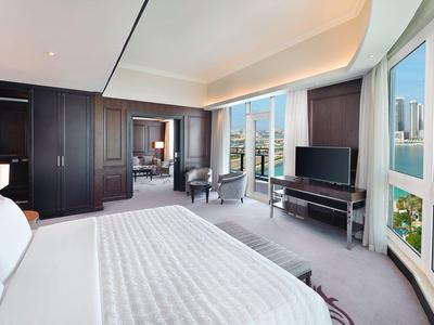 Heller Hotelraum mit großem Bett, Panoramafenstern und Blick auf Stadt und Wasser.