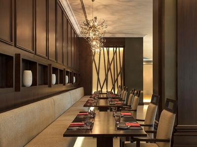 Elegantes Restaurant mit Holzmöbeln, bequemen Sitzbänken und dekorativer Beleuchtung.