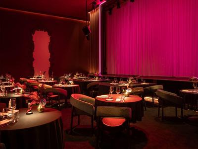 Elegantes Restaurant mit rundem Tischen, roten Stühlen und rotem Lichtambiente.