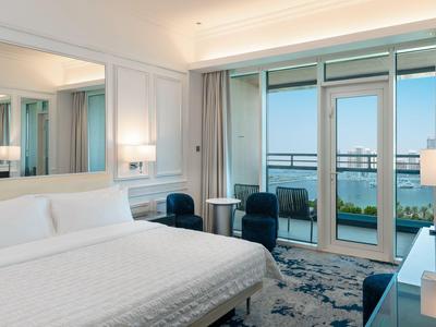 Elegantes Hotelzimmer mit Doppelbett, Sitzbereich und Balkon mit Meerblick.