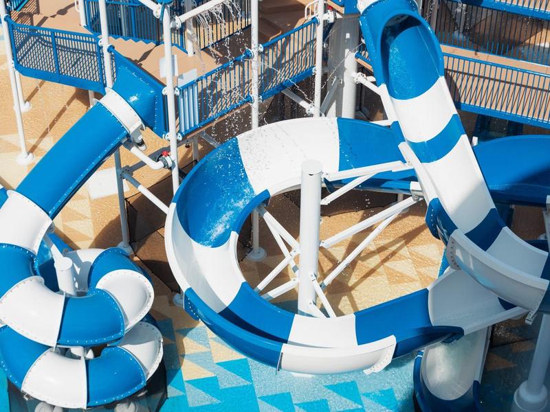 Große blaue und weiße Wasserrutschen in einem Schwimmbad mit Metalltreppen und Plattformen.