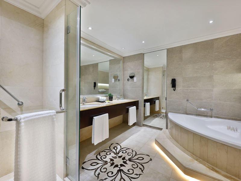 Moderne Badezimmer mit großer Badewanne, Glasdusche, Doppelwaschbecken und verzierten Bodenfliesen.