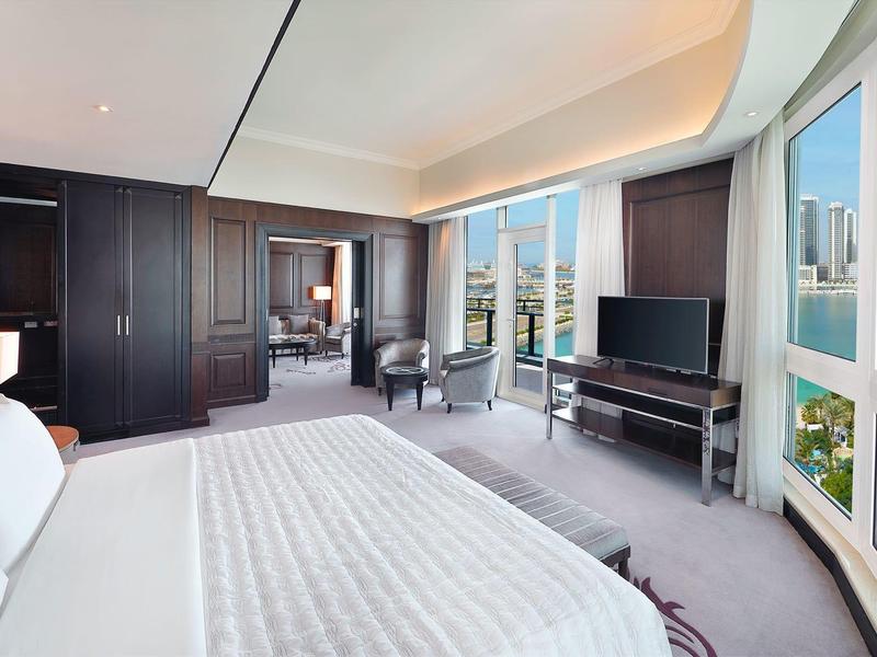 Heller Hotelraum mit großem Bett, Panoramafenstern und Blick auf Stadt und Wasser.