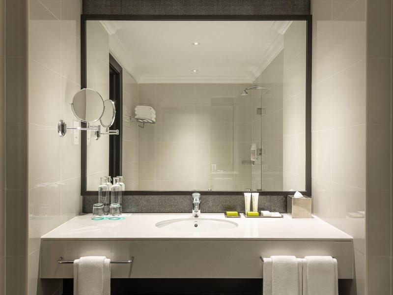 Modernes Badezimmer mit großem Spiegel, weißem Waschbecken und zwei Handtüchern unter der Theke.