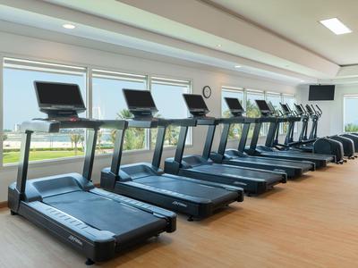 Mehrere Laufbänder in einem hellen Fitnessraum mit großen Fenstern und Blick ins Freie.