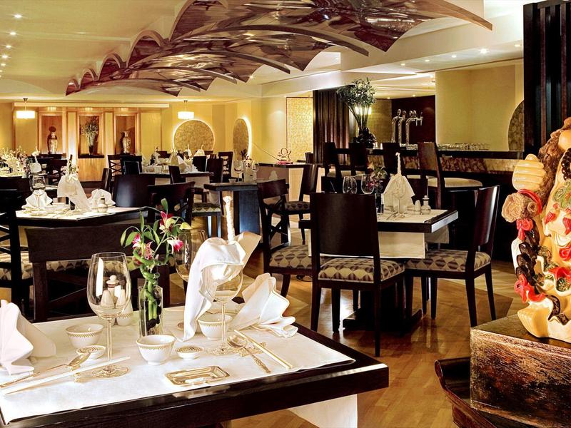 Elegantes Restaurant mit gedeckten Tischen und warmem Ambiente in einem Hotel.