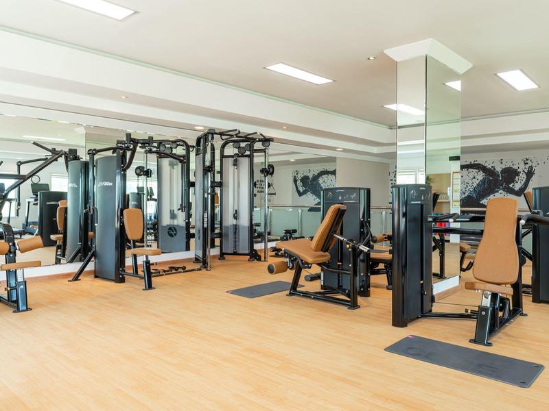 Helles Fitnessstudio mit modernen Trainingsgeräten und Holzfußboden in einem Hotel.