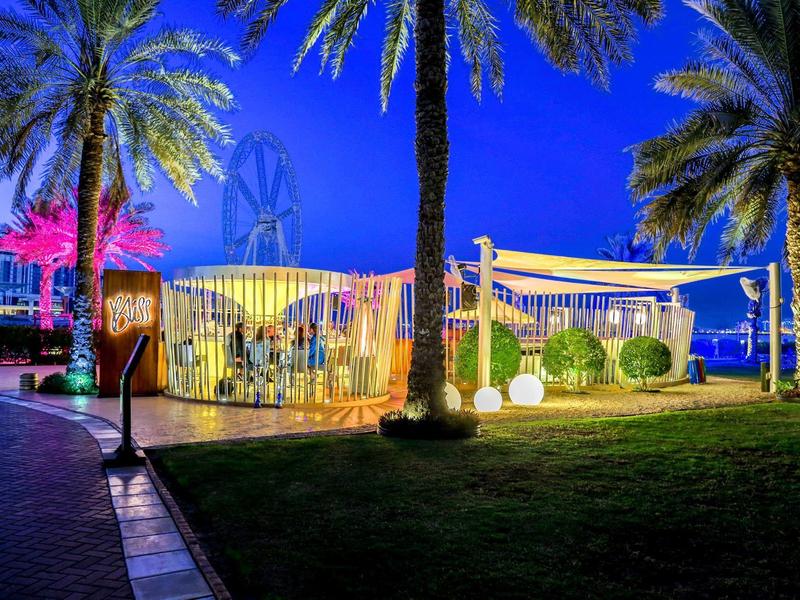 Beleuchtetes Open-Air-Restaurant mit Palmen bei Nacht in einer tropischen Hotelanlage.