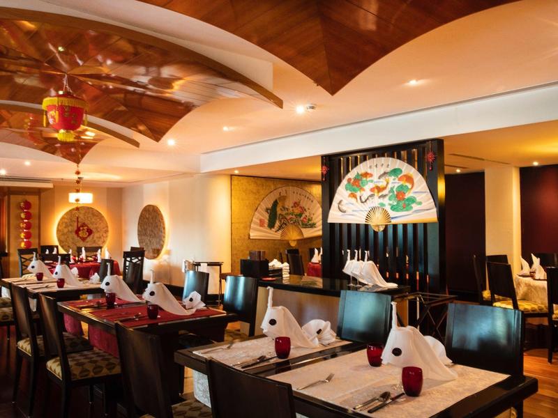 Elegantes Restaurant mit gedeckten Tischen, warmem Licht und dekorativer Decke in einem Hotel.