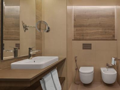 Modernes Hotelbadezimmer mit Waschbecken, Toilette und Bidet in warmen Brauntönen.