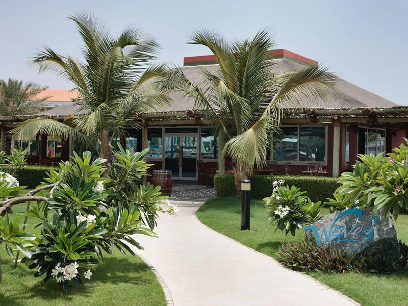 Ein tropisches Resort mit Palmen, grünem Rasen und einem Weg zur großen Veranda.