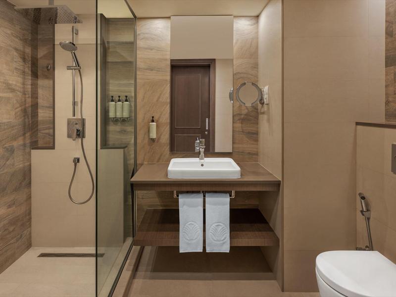 Modernes Badezimmer mit Dusche, Waschbecken, Spiegel und Toilette in warmen Brauntönen.