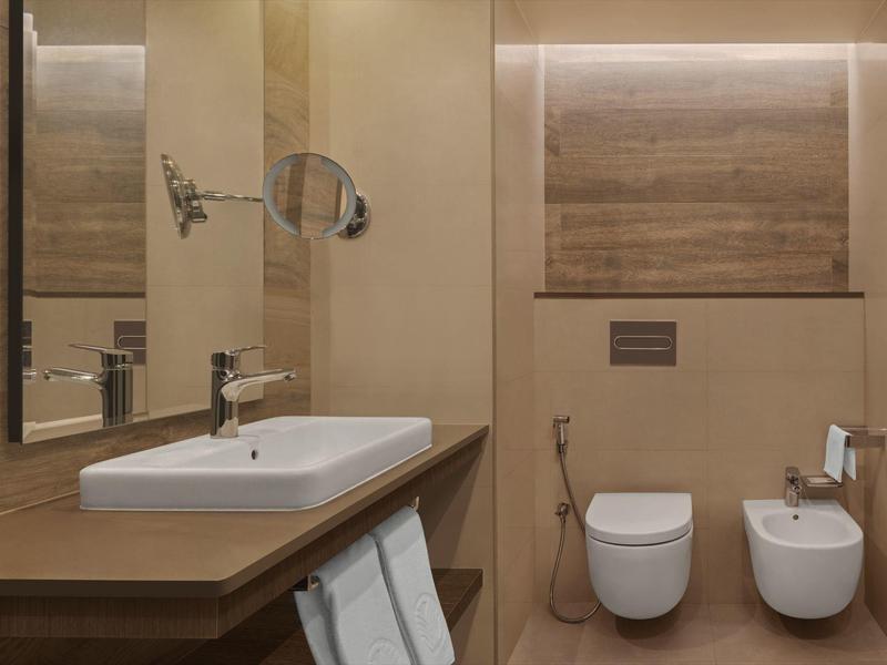 Modernes Hotelbadezimmer mit Waschbecken, Toilette und Bidet in warmen Brauntönen.