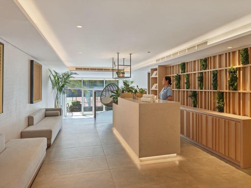 Helle, moderne Rezeption mit Holzregalen, Pflanzen und gemütlichen Sitzgelegenheiten.